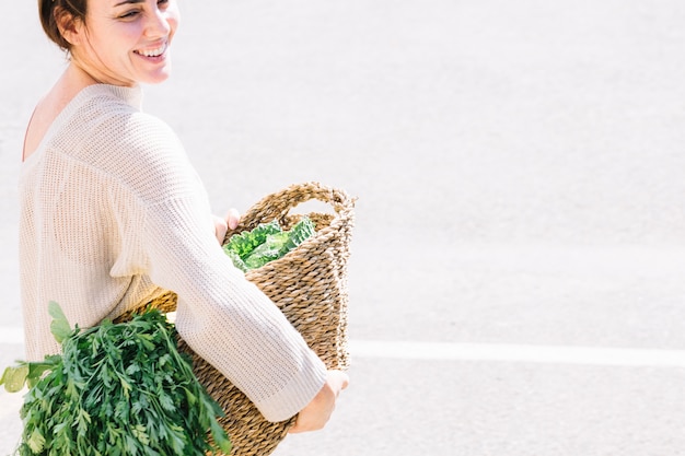 Joyeuse femme tenant le panier avec des légumes