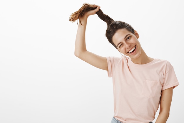 Joyeuse fille belle et heureuse posant contre le mur blanc