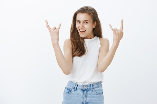 Joyeuse fille blonde optimiste montrant le geste du rock-n-roll, s'amuser, profiter d'un concert