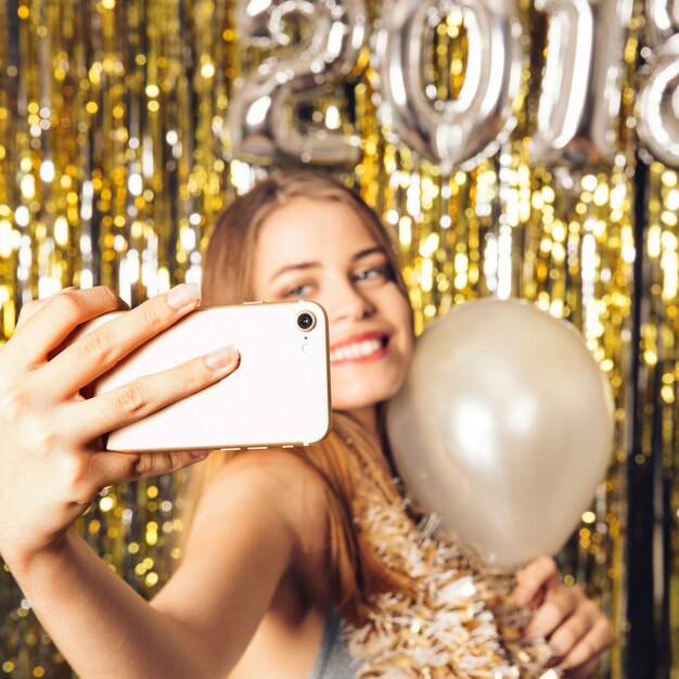 Joyeuse fille prenant selfie sur la fête du nouvel an