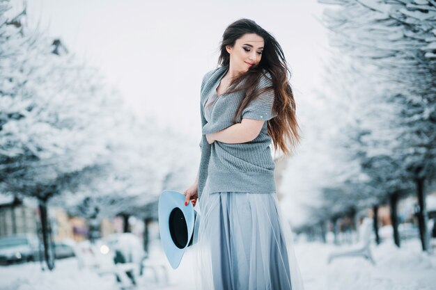 Joyeuse fille en robe d&#39;été légère, pull et chapeau se promène le long de l&#39;allée du parc