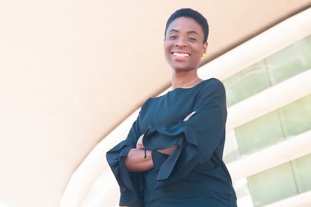 Joyeuse heureuse femme noire posant avec les bras croisés