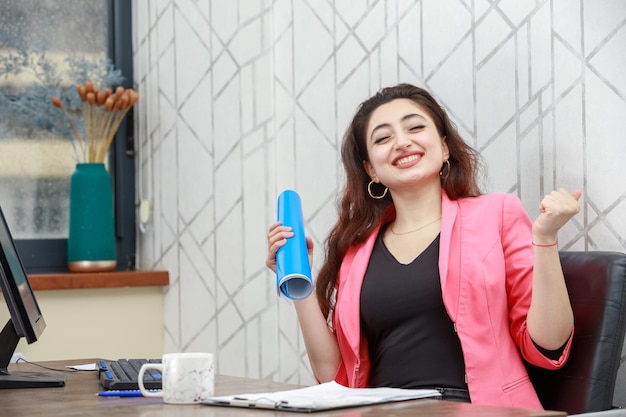 Joyeuse jeune femme assise derrière le bureau et se sentant heureuse