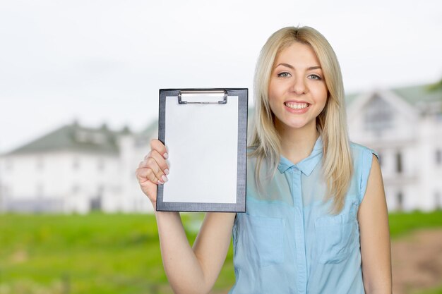 Joyeuse jeune femme attirante montrant le presse-papiers vide