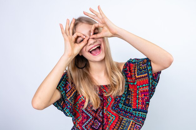 Joyeuse jeune femme blonde regardant à travers ses doigts