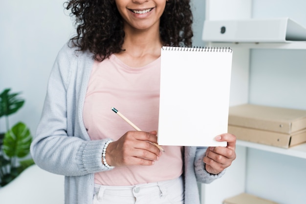 Photo gratuite joyeuse jeune femme montrant le bloc-notes