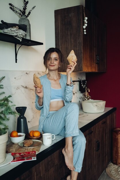 Joyeuse jeune femme posant avec des pâtisseries dans la cuisine