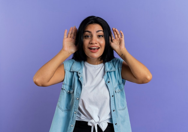 Joyeuse jeune femme de race blanche tient les mains près de la tête isolée sur fond violet avec espace copie