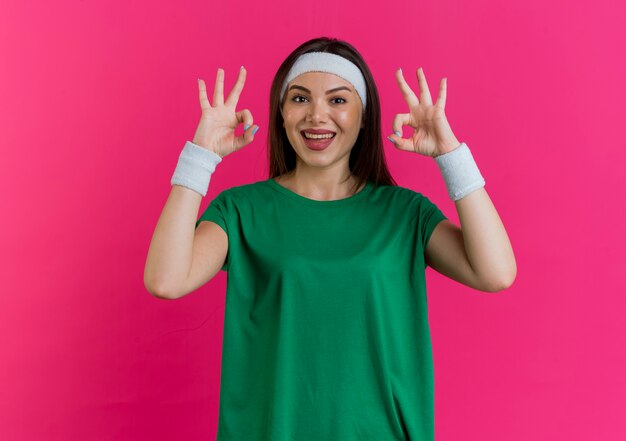Joyeuse jeune femme sportive portant bandeau et bracelets à faire signe ok