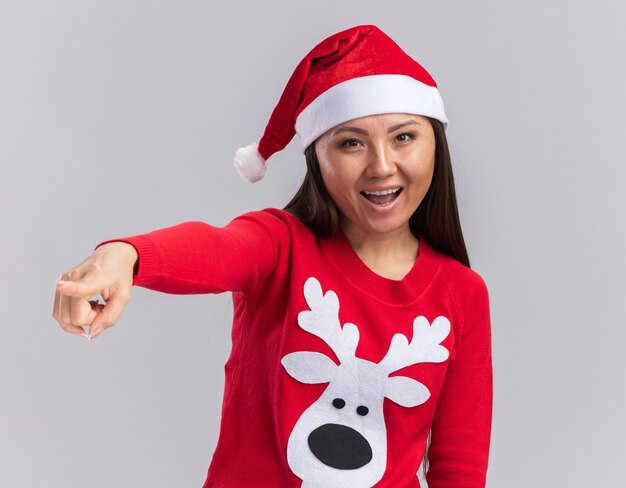 Joyeuse jeune fille asiatique portant un chapeau de Noël avec des points de chandail sur le côté isolé sur fond blanc