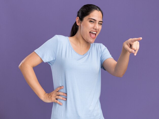 Joyeuse jeune fille brune caucasienne pointant sur le côté violet