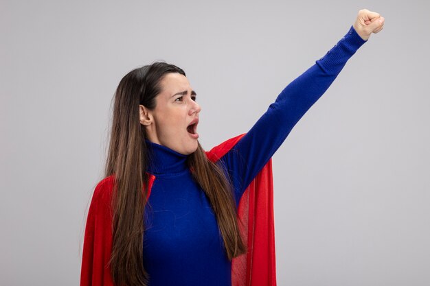 Joyeuse jeune fille de super-héros regardant côté levant le poing isolé sur fond blanc