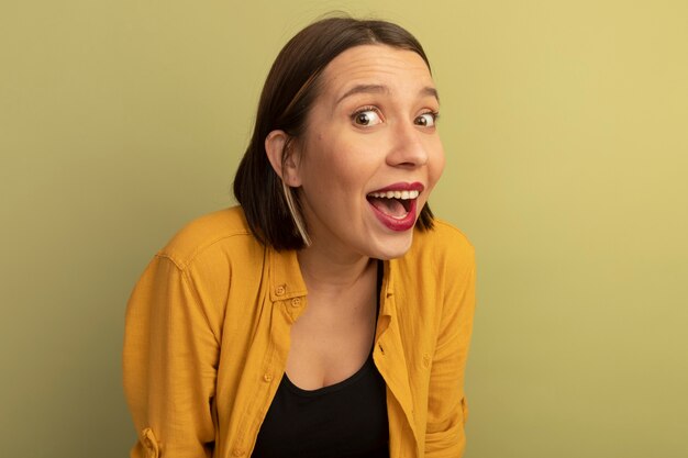 Joyeuse jolie femme regarde à l'avant isolé sur mur vert olive