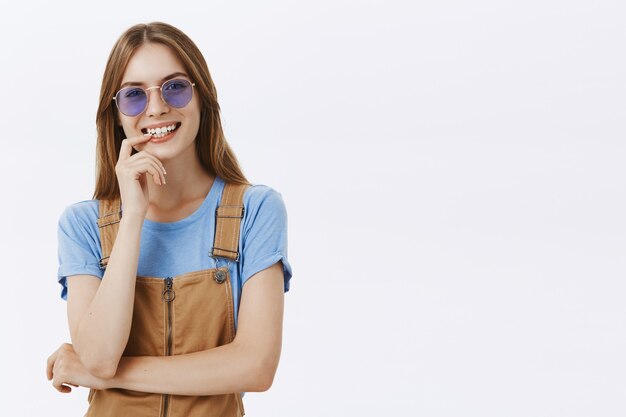 Joyeuse jolie fille heureuse à lunettes de soleil en riant et souriant sans soucis