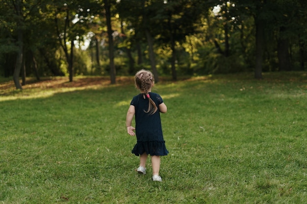 Joyeuse petite fille qui court sur l'herbe verte