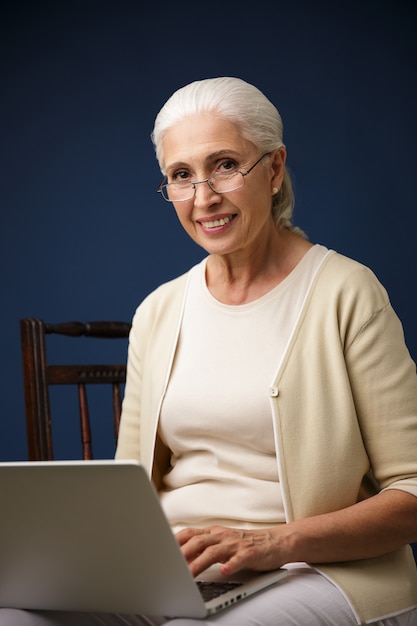 Joyeuse vieille femme à l'aide d'un ordinateur portable.