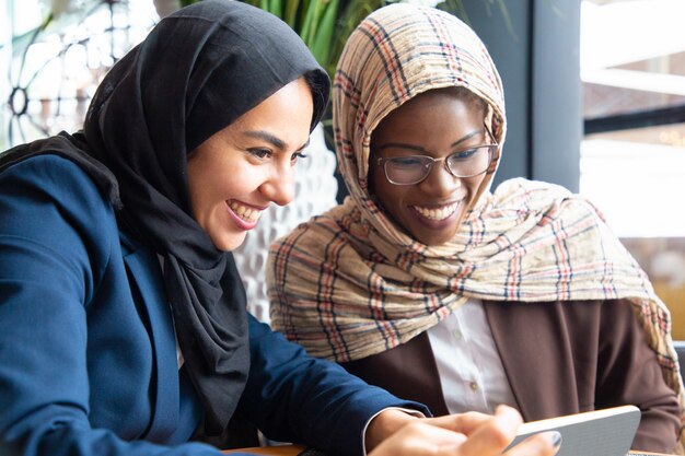 Joyeuses collègues féminines regardant du contenu au téléphone