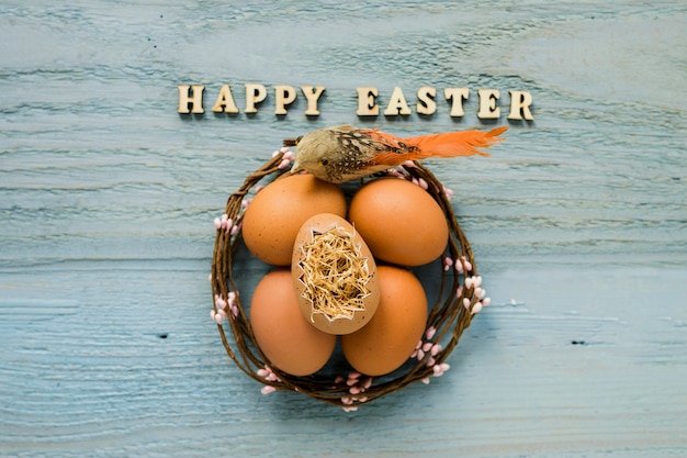 Photo gratuite joyeuses pâques écrit près de l'oiseau et des oeufs