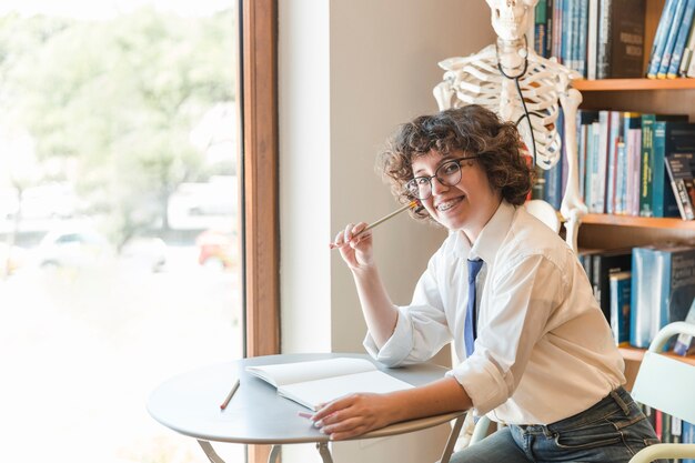 Joyeux adolescent assis près de la fenêtre de la bibliothèque