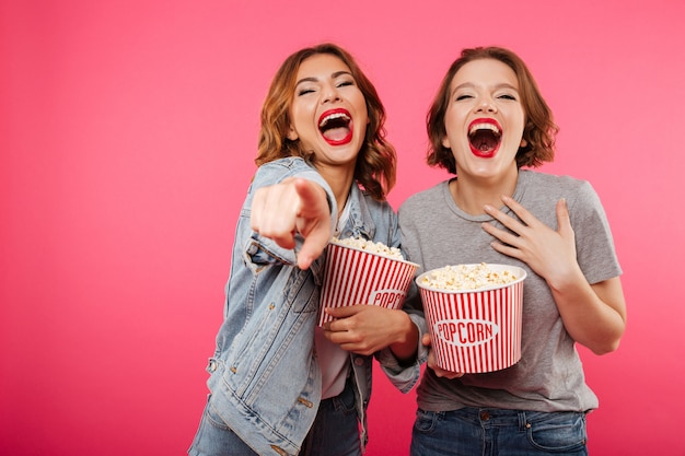 Joyeux Amis Femmes Riant Manger Du Pop-corn Regarder Le Film Pointant.