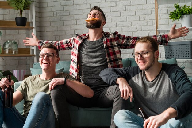 Joyeux amis masculins ayant de la pizza et de la bière et regardant le sport à la télévision