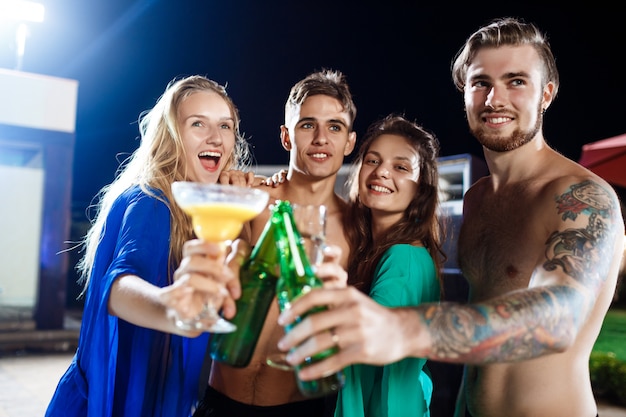 Joyeux amis souriant, se réjouissant, se reposant à la fête près de la piscine