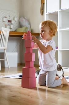 Joyeux arrangement pour tout-petits cubes roses assemblant les matériaux éducatifs de la tour maria montessori
