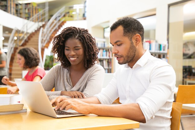 Joyeux collègues assis à la bibliothèque et en communication