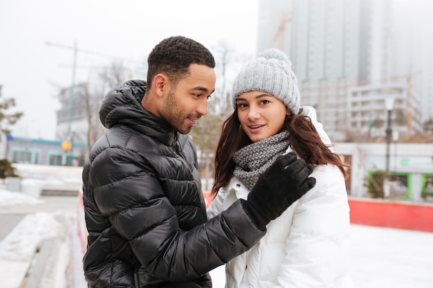 Joyeux couple d'amoureux patinant à la patinoire à l'extérieur.