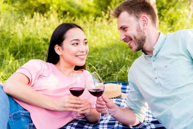 Joyeux couple amoureux portant des verres à vin sur un pique-nique dans la nature