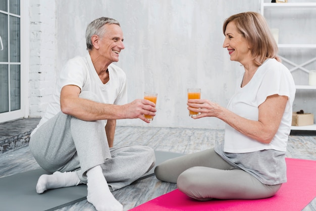 Joyeux couple appréciant les jus de fruits après le yoga