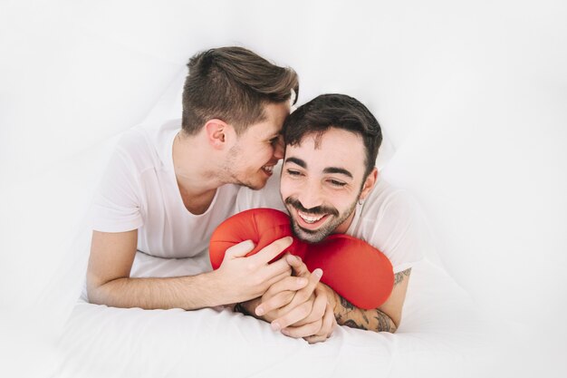 Joyeux couple gay avec oreiller dans son lit