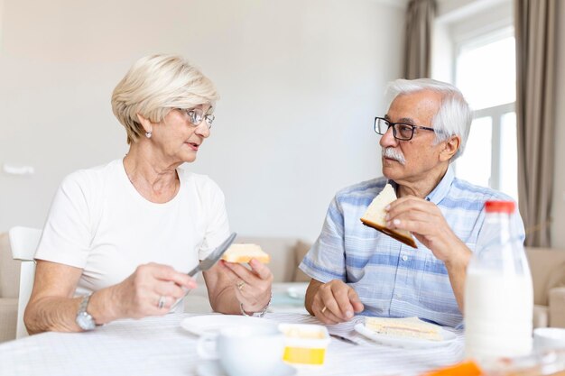 Joyeux couple de personnes âgées prenant son petit déjeuner à la maison