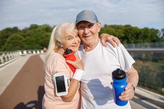 Joyeux Couple De Personnes âgées S'étreignant à L'entraînement Sur La Passerelle De La Ville Vide Photo Premium