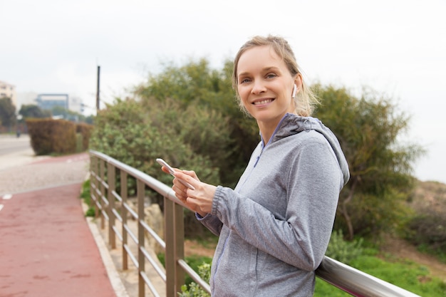 Joyeux coureur de femme choisissant la musique pour un entraînement en plein air