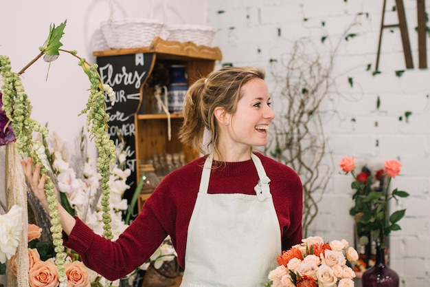 Photo gratuite joyeux fleuriste montrant des fleurs dans la boutique