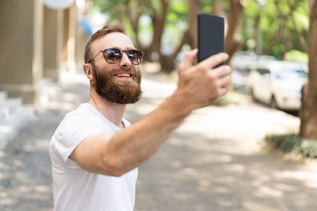 Joyeux hipster guy prenant selfie