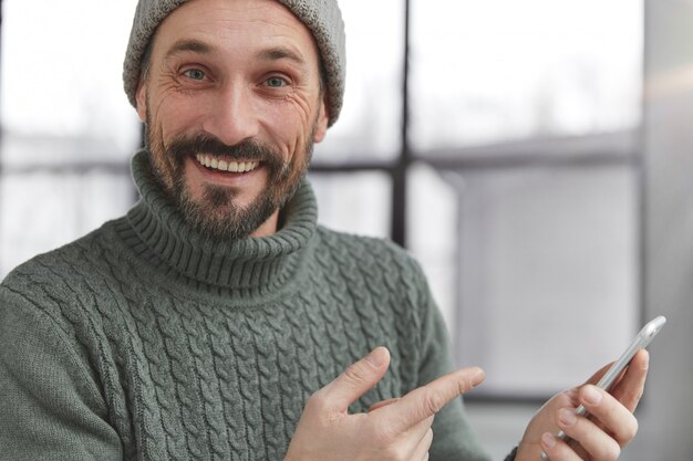 Joyeux homme barbu portant un pull chaud tricoté et un chapeau