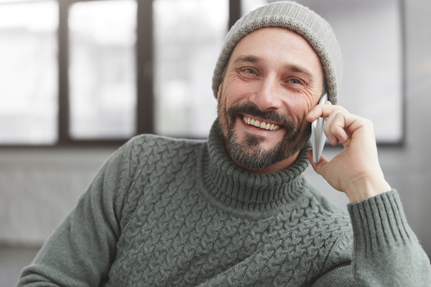 Joyeux homme barbu portant un pull chaud tricoté et un chapeau