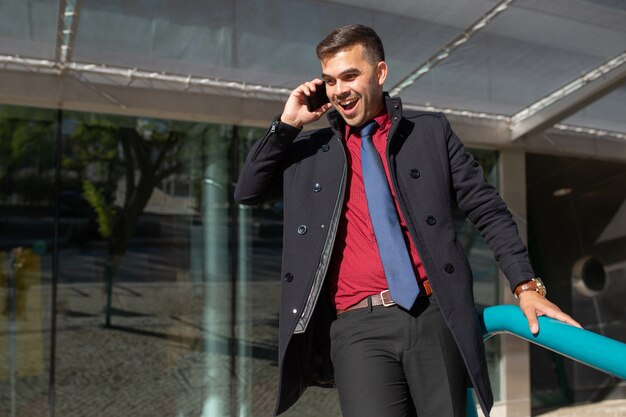 Joyeux homme excité parlant au téléphone et descendant les escaliers