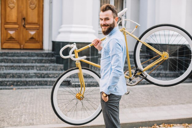 Joyeux homme transportant un vélo sur l&#39;épaule