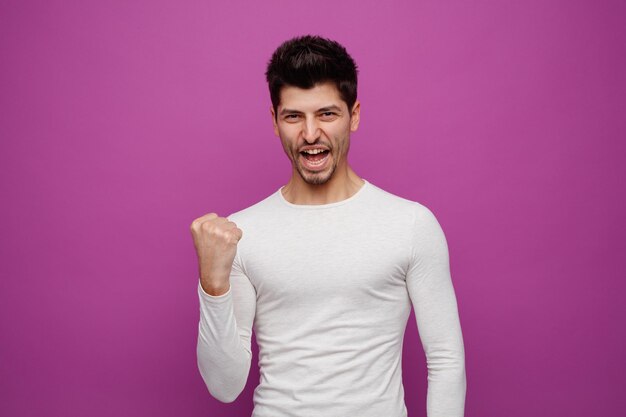 Joyeux jeune bel homme regardant la caméra faisant un geste oui sur fond violet