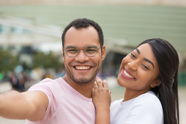 Joyeux jeune couple posant pour selfie dans la rue