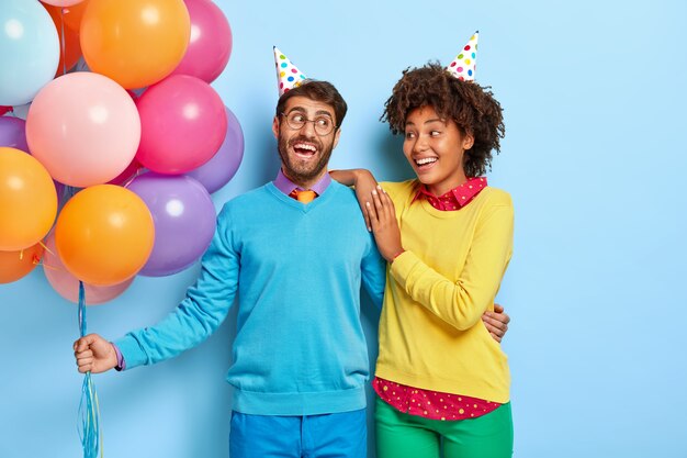 Joyeux jeune couple positif lors d'une fête posant avec des ballons