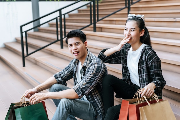 Joyeux jeune couple tenant plusieurs sacs à provisions en papier