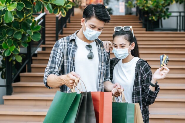 Joyeux jeune couple tenant plusieurs sacs à provisions en papier