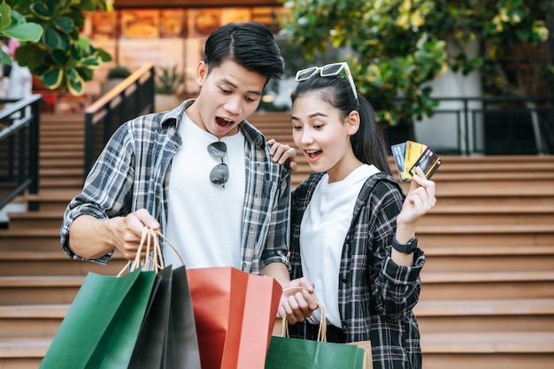 Joyeux jeune couple tenant plusieurs sacs à provisions en papier