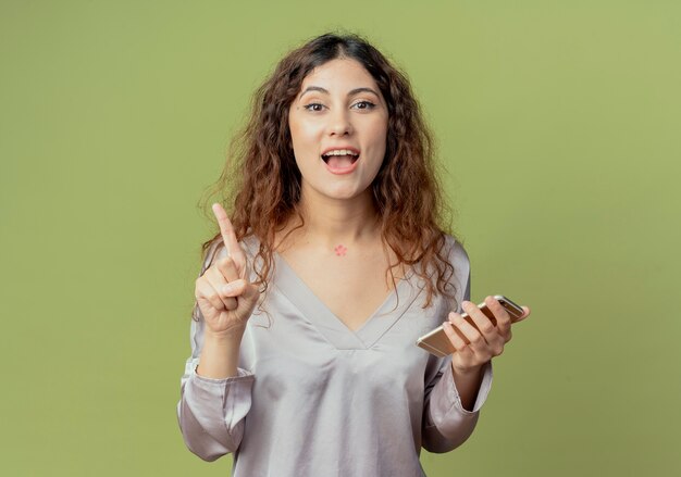 joyeux jeune employé de bureau jolie femme tenant le téléphone et les points sur le côté