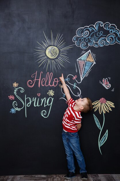 Joyeux jeune enfant debout et pointant vers le printemps bonjour