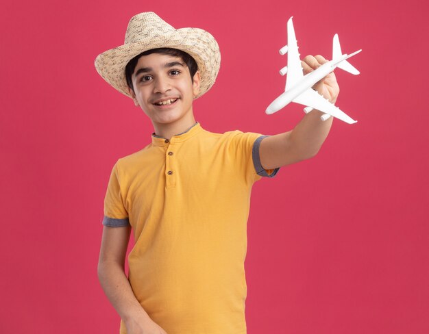 Joyeux jeune garçon caucasien portant un chapeau de plage et tenant un jouet d'avion